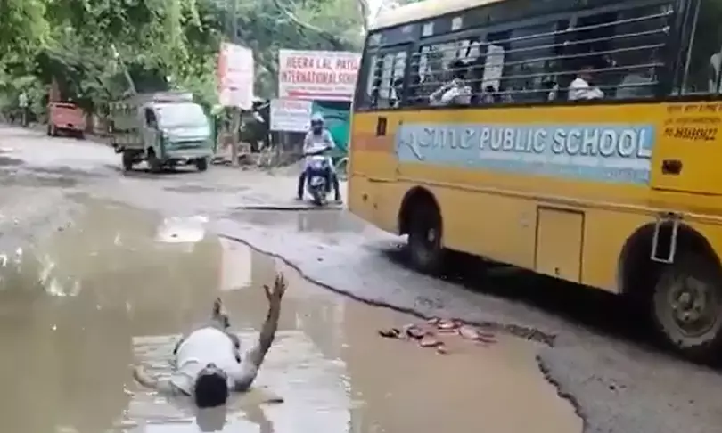 गड्ढे में गिरी बेटी तो सड़कों की पोल खोलने को कीचड़ में लेटा पिता
